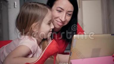母亲和小女儿在<strong>数码</strong>平板电脑上网上购物时看鞋<strong>类</strong>。 网上购物的概念